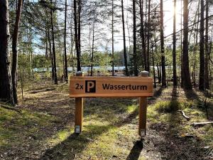 a wooden sign in the middle of a forest at Wasserturm Spreewitz in Spreewitz