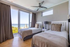 a bedroom with two beds and a large window at Seascape in Plettenberg Bay +27 photos