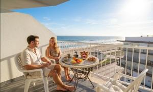 a man and a woman sitting at a table on a balcony at Apartamento con vistas a la Playa con Ascensor y WIFI 9 pax in Daimuz