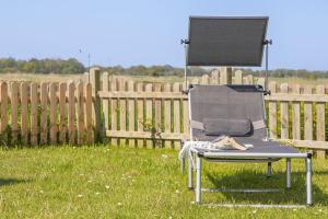 a chair sitting in the grass in front of a fence at Ferienhaus Robby in Stedesdorf