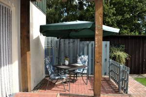 a table and chairs under an umbrella on a patio at Neue moderne Ferienwohnung, separater Eingang, Seenähe in Möllen
