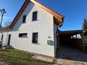 a white house with a wooden garage at Fleesenseetreppe rechts in Göhren-Lebbin +9 photos