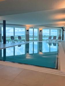 a large swimming pool with chairs in a building at Residenz Bollwark 3 1 in Olpenitz