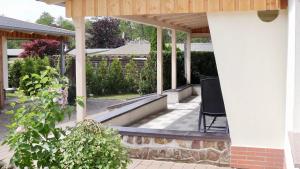 a porch of a house with a black chair at Bungalow am See in Basedow