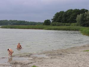 two men are standing in the water on a beach at Bungalow am See in Basedow