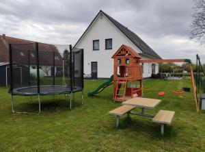 a playground with a house and a play structure at Rügen Fewo 301 in Haidhof