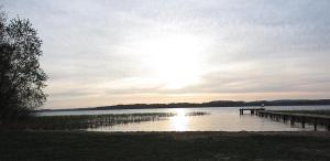 a dock on a lake with the sun in the sky at Bungalow Wallner in Basedow