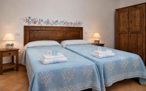 a bedroom with two beds with blue sheets and towels at Big Pevero Sea View House 8 Three Bedrooms in Porto Cervo +6 photos