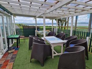 a patio with chairs and a table and a white pergola at Shannon Estuary Glamping Budget-Sustainable-Biodiversity Habitat--Rustic-Countryside Holiday Accommodation in Effernan