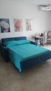 a blue bed in a room with pictures on the wall at Nenni House in Sassari
