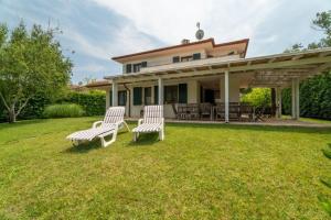 two white chairs sitting on a lawn in front of a house at D Oro in Caleri