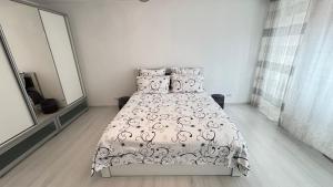a bedroom with a bed with a black and white bedspread at Apartament Ultra-Central Rm Valcea in Râmnicu Vâlcea