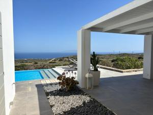a white house with a swimming pool and the ocean at villa zakintos in Aspro Chorio Paros