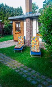 two chairs sitting in the grass in front of a house at Gemütliche Ferienwohnung Löbert in Lübbenau