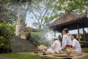 a group of people sitting on the grass in front of a building at The Lokha Ubud Resort, Villas & SPA in Ubud