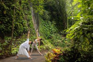 a woman is dancing in the forest near a waterfall at The Lokha Ubud Resort, Villas & SPA in Ubud