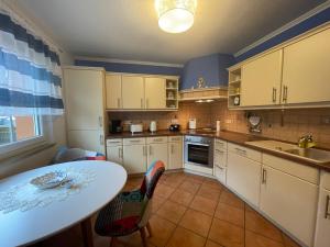 a kitchen with white cabinets and a table and chairs at Ferienwohnung Bunte Wiese in Parchtitz