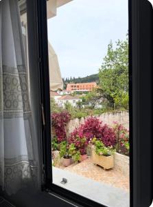 a window with a view of a garden with flowers at Μαργαρίτα 1 in Fiskardo