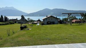 a large grassy field with a house and the water at Wild und Wald Ferienwohnung in Steinbach am Attersee
