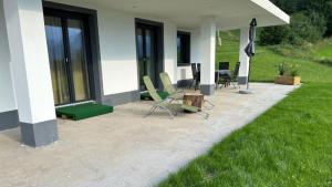 a patio of a house with chairs and a table at Wild und Wald Ferienwohnung in Steinbach am Attersee