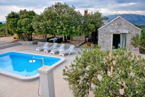 an outdoor swimming pool with chairs and a house at Holiday Home Sweet Dreams in Pučišća