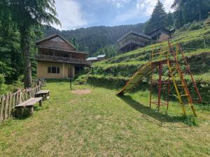 a playground with a slide and a bench in a field at Mid Conifer Cottage Villa in Dalhousie