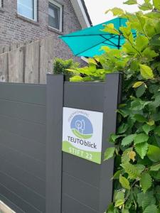 a sign in front of a fence with a blue umbrella at Ferienwohnung Teutoblick Leeden in Tecklenburg