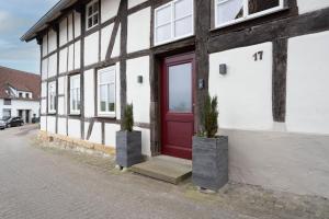 a red door on a white building with two potted plants at MispelFachwerkOase in Tecklenburg