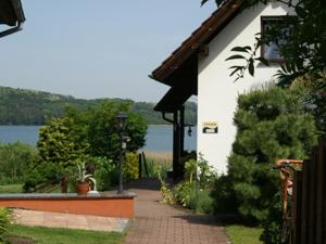 a building with a walkway next to a body of water at Chalet am See in Waldsieversdorf