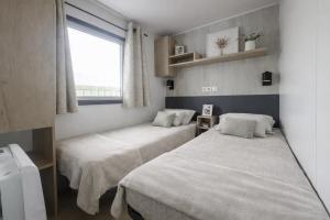 two beds in a small room with a window at Beachside Vakantiepark in Blankenberge