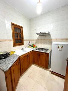 a kitchen with wooden cabinets and a white refrigerator at Tamezda 4 in Taguermess