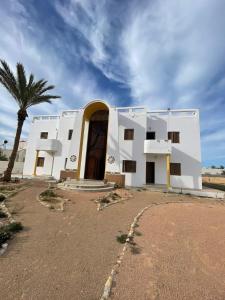 a white building with a palm tree in front of it at Tamezda 4 in Taguermess +10 photos