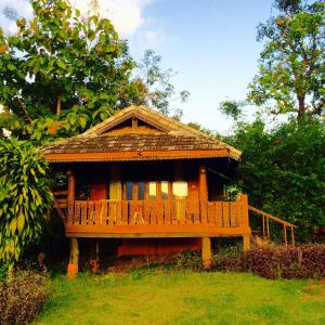 een houten huis met een terras in het gras bij Romantic Time Mountain Resort in Pai