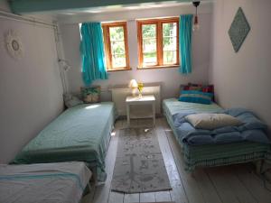 two beds in a room with blue curtains at Hasselsro in Tranekær