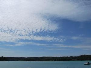 a cloudy sky over a lake with a boat at Ferien am Roten Haus in Buckow +5 photos