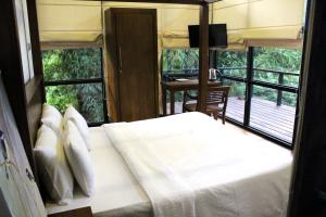 Schlafzimmer mit einem großen weißen Bett und Fenstern in der Unterkunft The Country House Chalets in Galle