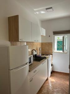 a kitchen with white cabinets and a white refrigerator at Apartment Sole in Poreč