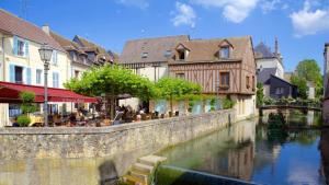 a river in a town with people sitting at tables next to buildings at T2 lumineux, moderne, calme & central à Montargis in Montargis