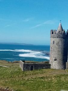 a castle on a hill with the ocean in the background at Radharc soiléir in Doolin