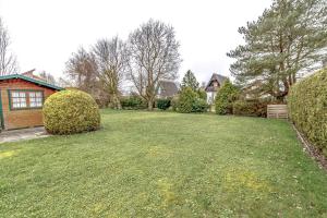 a large yard with two bushes and a house at Ferienhaus Mina in Neuharlingersiel