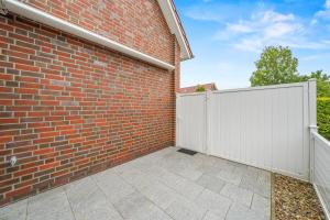 a brick building with a white fence and a gate at Ferienwohnung Hamtor in Bensersiel
