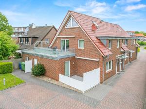a red brick house with a balcony on a street at Ferienwohnung Hamtor in Bensersiel +14 photos