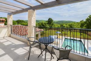 a balcony with a table and chairs and a swimming pool at Villa Fortuna - Private Pool and Garden Retreat in Labin