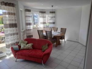 a living room with a red chair and a table at Ferienwohnung Groß in Bermatingen