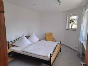 a bedroom with a bed with white sheets and a chair at Ferienwohnung Groß in Bermatingen