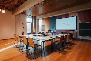 ein Konferenzraum mit einem langen Tisch, Stühlen und einem Bildschirm in der Unterkunft SeeLoge Eutin in Eutin