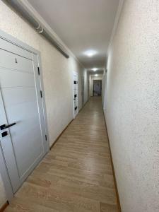 an empty hallway with a white door and a wooden floor at Мотель Эмир in Pokrovka