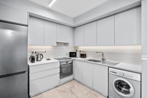 a kitchen with white cabinets and a washer and dryer at Latitudes 1 Bedroom Apartment in Meneou
