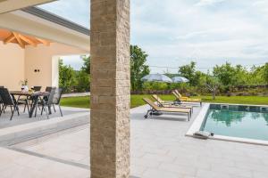 a patio with a table and chairs next to a pool at Villa Fortuna - Private Pool and Garden Retreat in Labin +28 photos