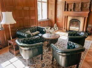 a living room with leather furniture and a fireplace at Gutshaus Gevezin in Blankenhof